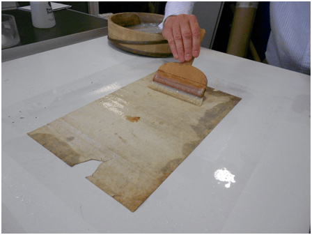 Lining a print. After the object was humidified, it was placed on a sheet of Melinex. The verso of the object was pasted with wheat starch paste using a Japanese brush.