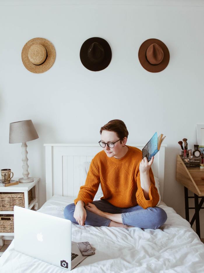 photo of person sitting on bed working on computer